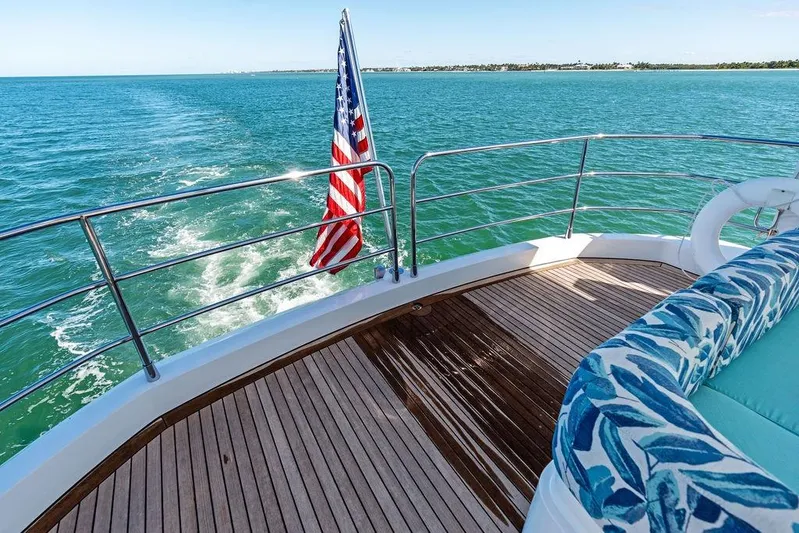 It's Enough Yacht Photos Pics Sunseeker Manhattan 73 yacht deck with American flag, cruising on blue ocean waters.