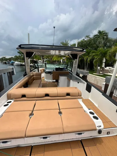  Yacht Photos Pics 2022 Aviara 32 boat with tan seating, docked by palm trees under cloudy skies.