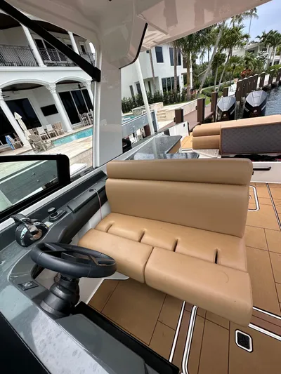  Yacht Photos Pics 2022 Aviara 32 boat interior with tan seating and modern steering, docked near luxury waterfront homes.