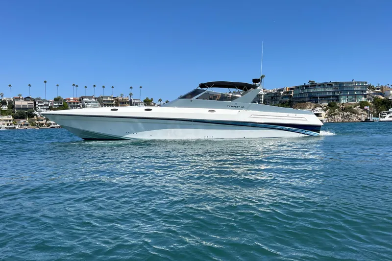 Fantom Yacht Photos Pics 1990 Tempest 60 Express yacht cruising on a sunny day near coastal homes.