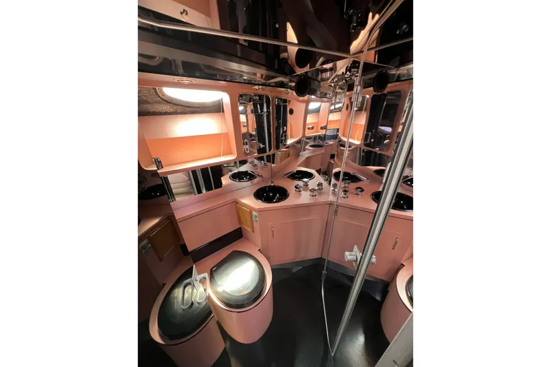 Fantom Yacht Photos Pics Luxurious 1990 Tempest 60 Express yacht bathroom with pink decor and mirrored surfaces.