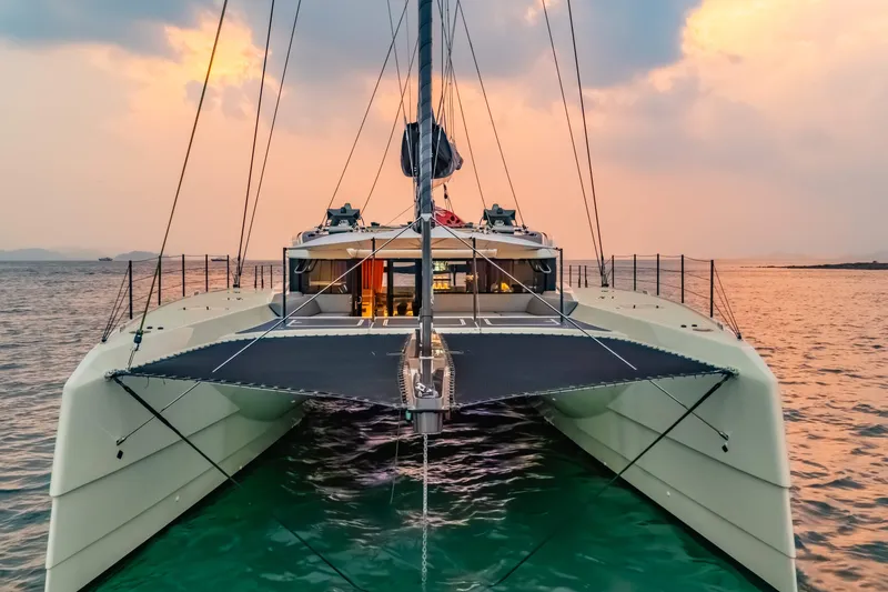 Jack Yacht Photos Pics 2023 McConaghy MC75 catamaran sailing at sunset on calm waters.