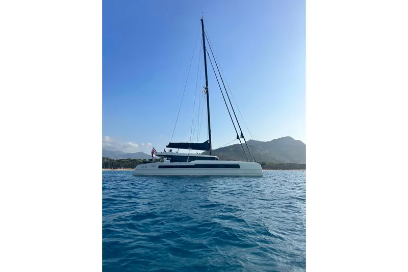 Jack Yacht Photos Pics 2023 McConaghy MC75 catamaran sailing near a scenic coastline with mountains.