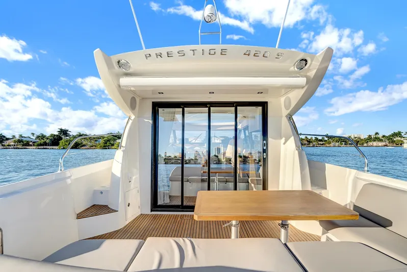 E Komo Mai Yacht Photos Pics 2022 Prestige 420S yacht with outdoor seating, table, and scenic water view.