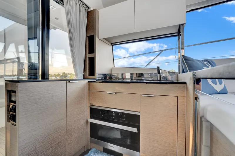 E Komo Mai Yacht Photos Pics Modern kitchen interior on 2022 Prestige 420S yacht with sleek cabinetry and ocean view.