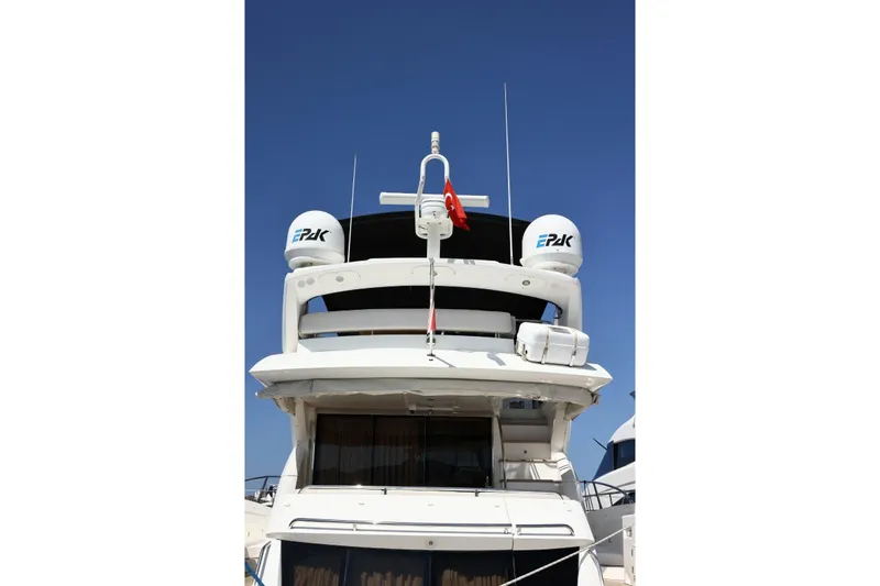  Yacht Photos Pics 2012 Sunseeker Manhattan 63 yacht, rear view with radar domes and flag, under clear blue sky.
