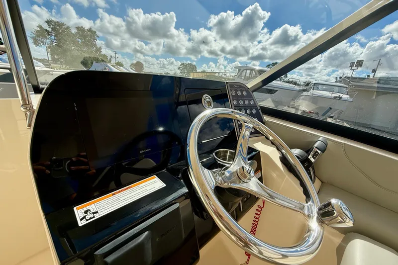  Yacht Photos Pics 2026 Scout 255 Dorado boat helm with steering wheel and control panel under sunny skies.