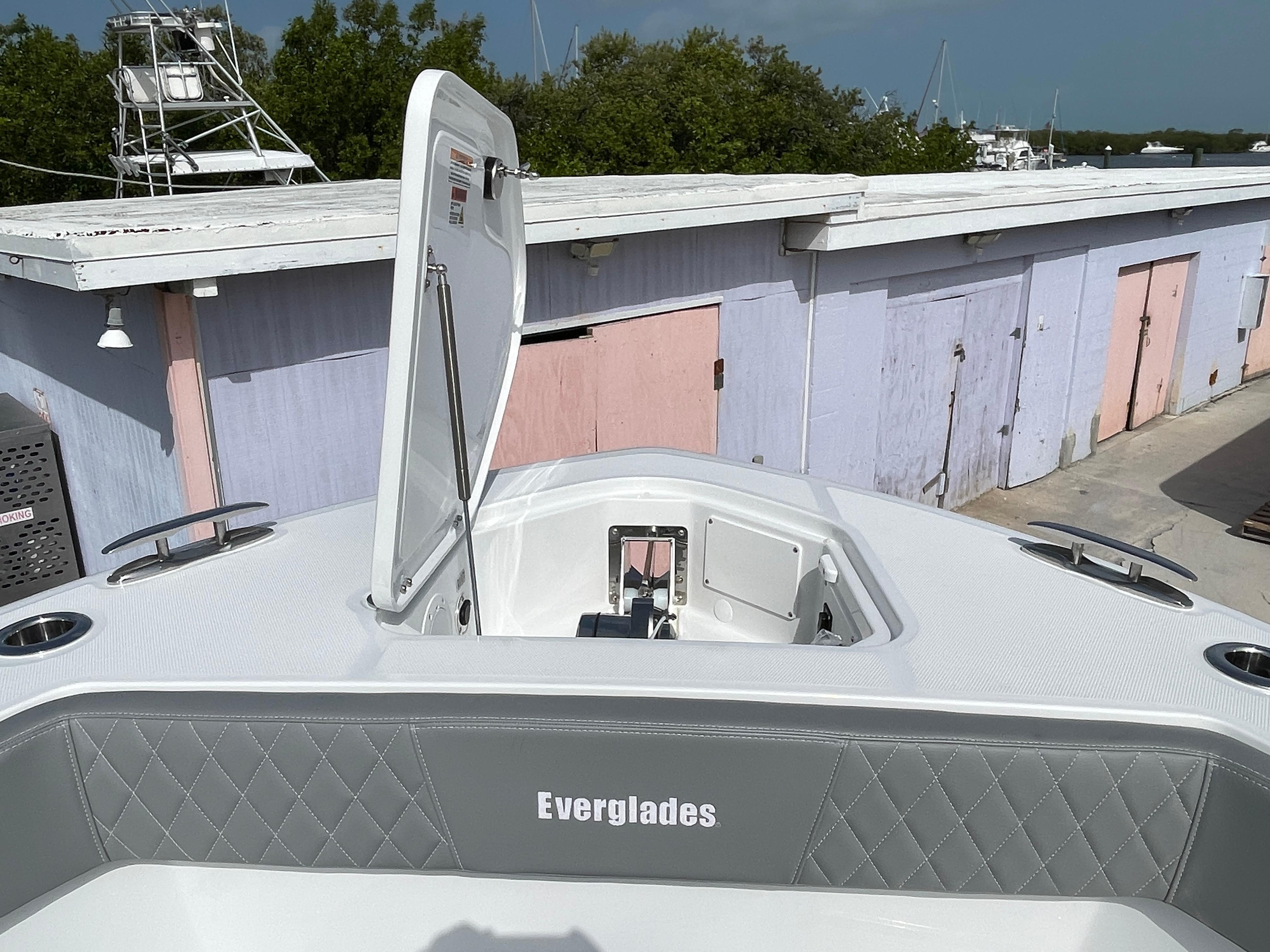 2026 Everglades 375cc boat with open hatch, docked near pastel-colored buildings.