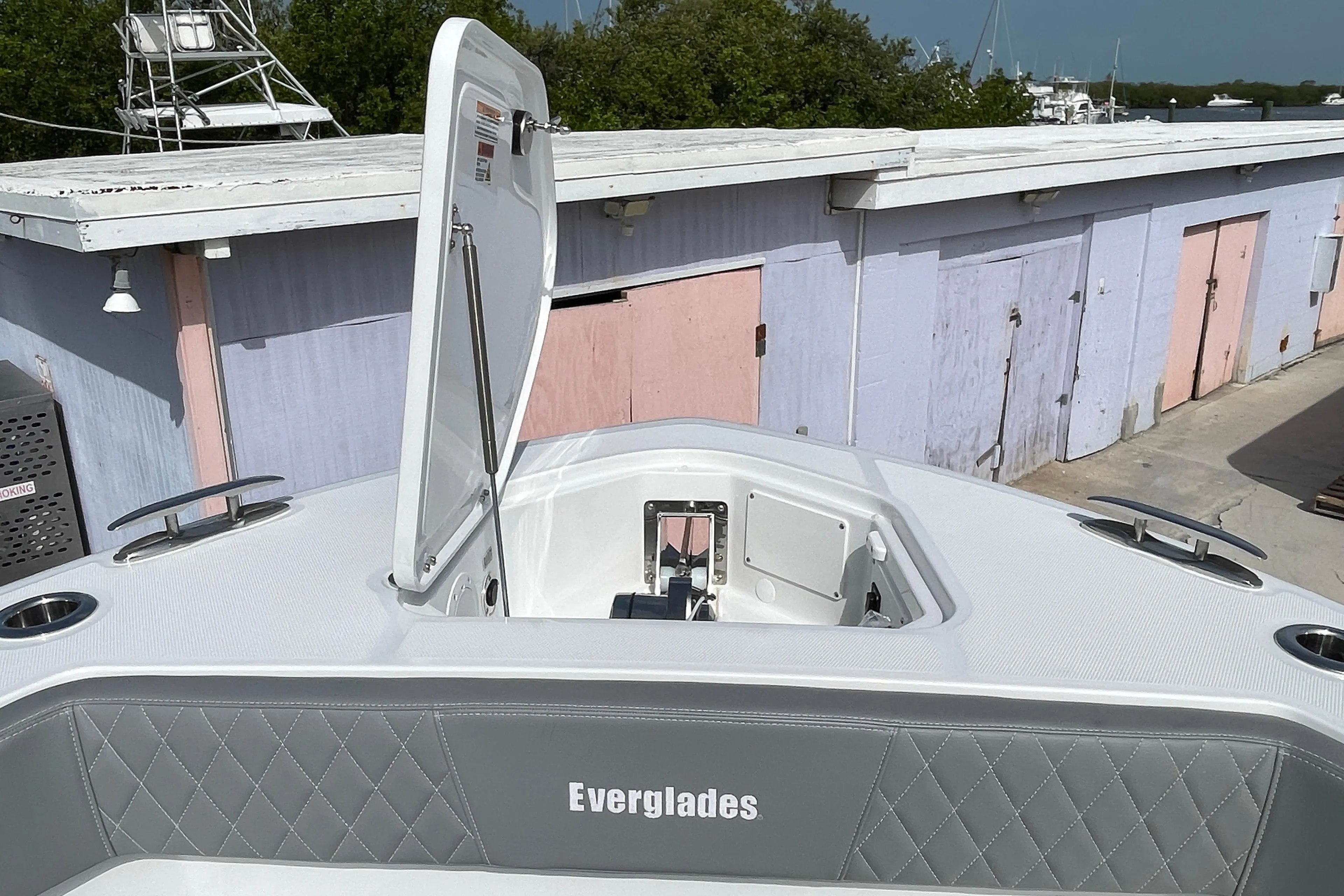 2026 Everglades 375cc boat with open hatch, docked near pastel-colored buildings.