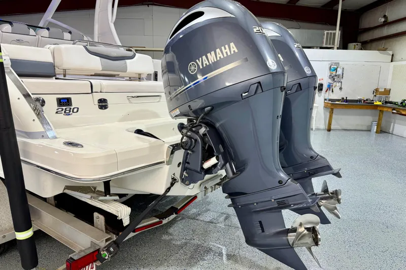 Yacht Photos Pics 2021 Chaparral 280 OSX boat with dual Yamaha outboard engines in a garage setting.