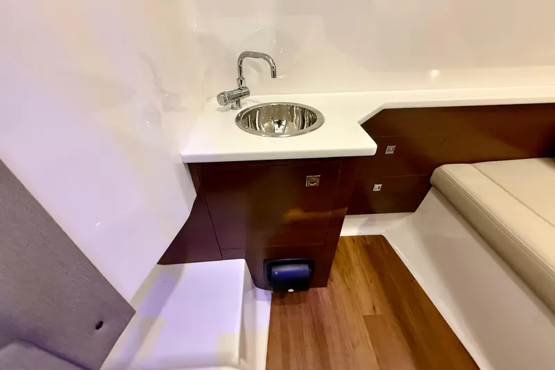  Yacht Photos Pics 2021 Chaparral 280 OSX interior with sink, wooden cabinetry, and cushioned seating.