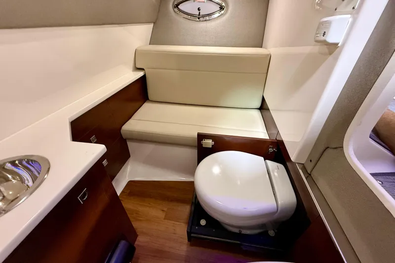  Yacht Photos Pics 2021 Chaparral 280 OSX boat interior with compact bathroom and seating area.
