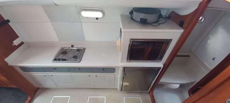 Zarafet Yacht Photos Pics Compact kitchen in a 1995 Prout 45 yacht with stove, oven, and storage.
