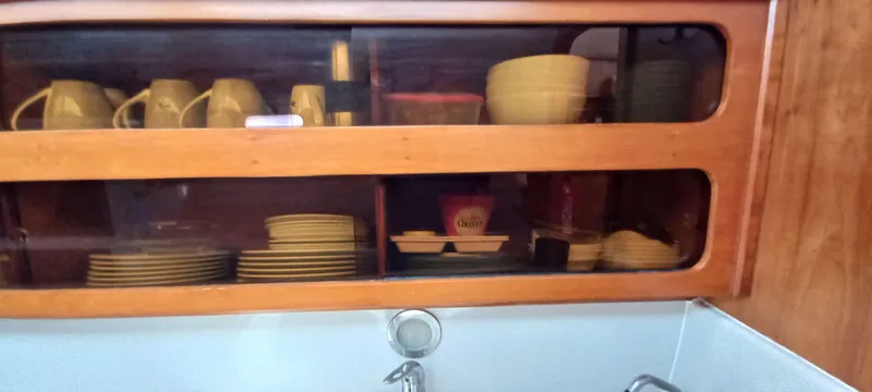 Zarafet Yacht Photos Pics Wooden kitchen cabinet with dishes and cups on a Prout 45, 1995 model.
