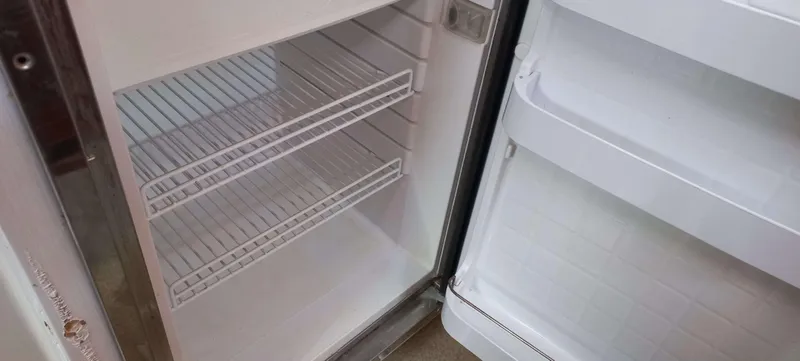 Zarafet Yacht Photos Pics Empty refrigerator interior with open door, featuring wire shelves.