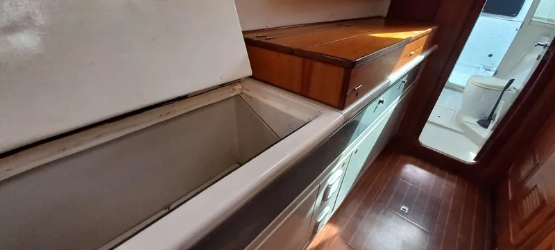 Zarafet Yacht Photos Pics Interior of 1995 Prout 45 yacht showing kitchen area with wooden cabinetry and flooring.
