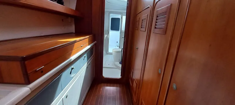 Zarafet Yacht Photos Pics Interior of a 1995 Prout 45 yacht, featuring wooden cabinetry and hallway leading to bathroom.