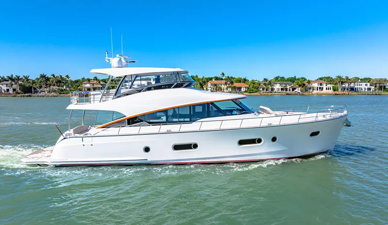 Dog House Yacht Photos Pics 2025 Belize 66 Daybridge yacht cruising on a sunny day, with waterfront homes in the background.