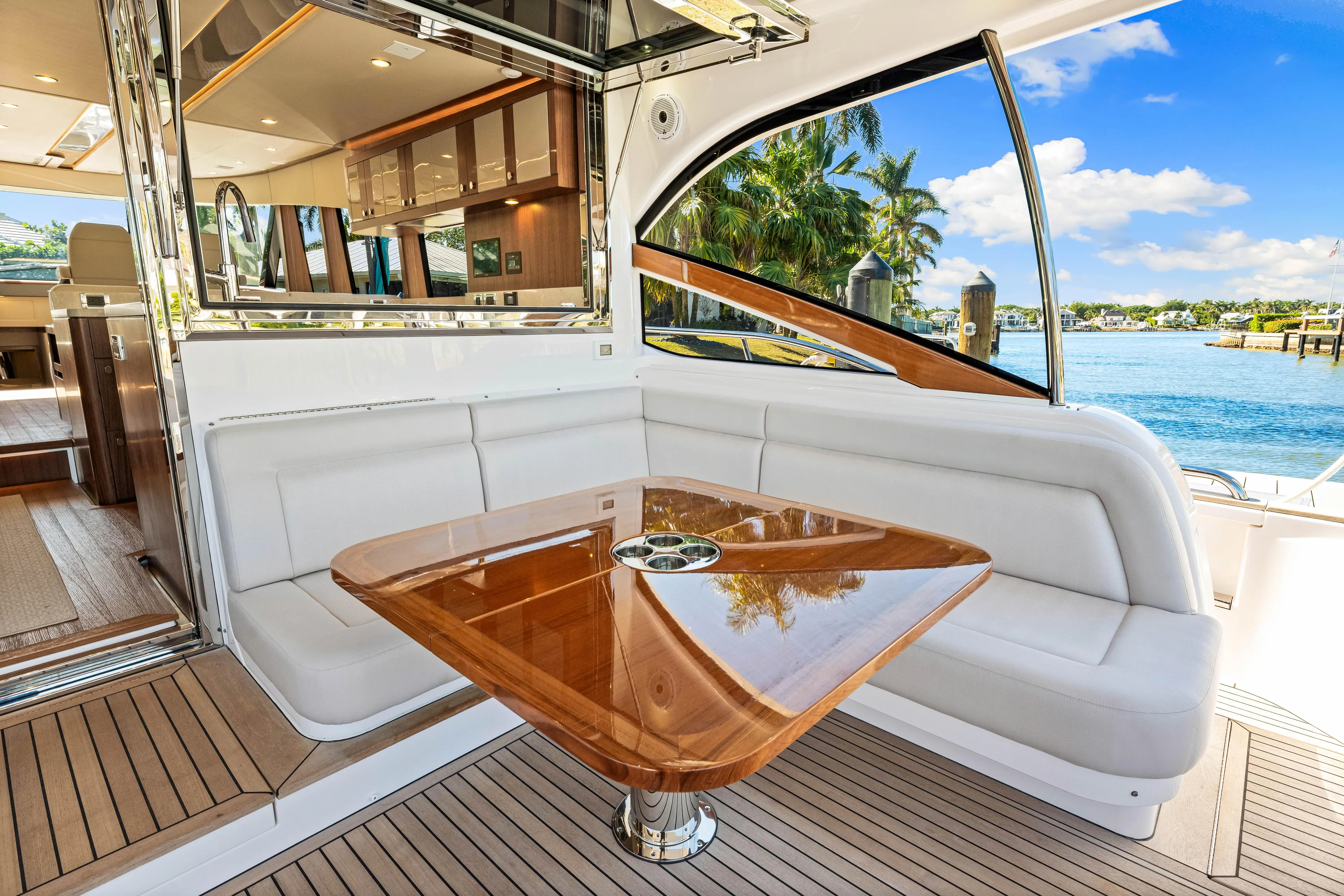 Dog House Yacht Photos Pics Luxurious seating area on 2025 Belize 66 Daybridge yacht with wooden table and scenic water view.