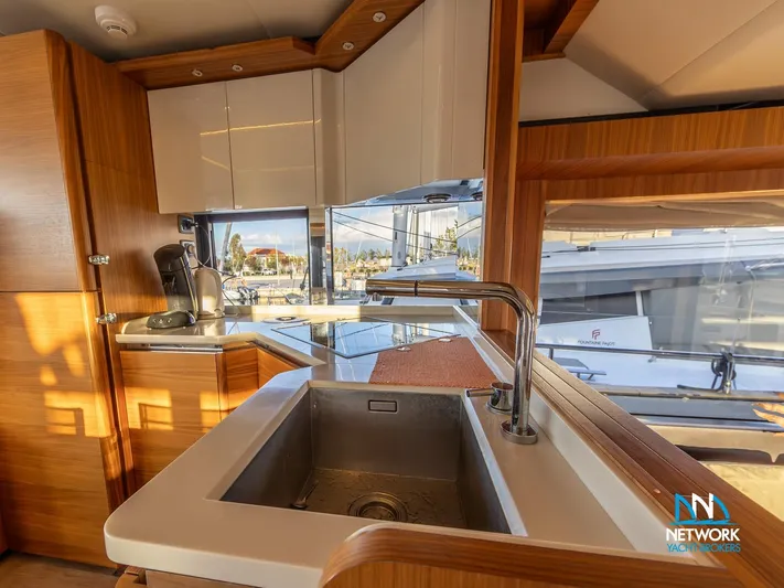  Yacht Photos Pics Modern kitchen interior of 2017 Absolute NAVETTA 58 yacht with sink and wooden cabinetry.