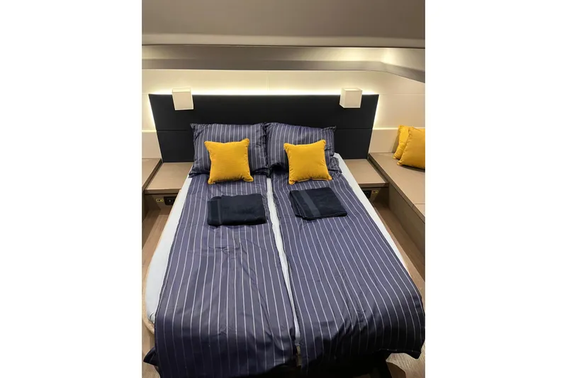  Yacht Photos Pics Luxurious cabin interior of 2024 Beneteau Gran Turismo 45 with striped bedding and yellow cushions.
