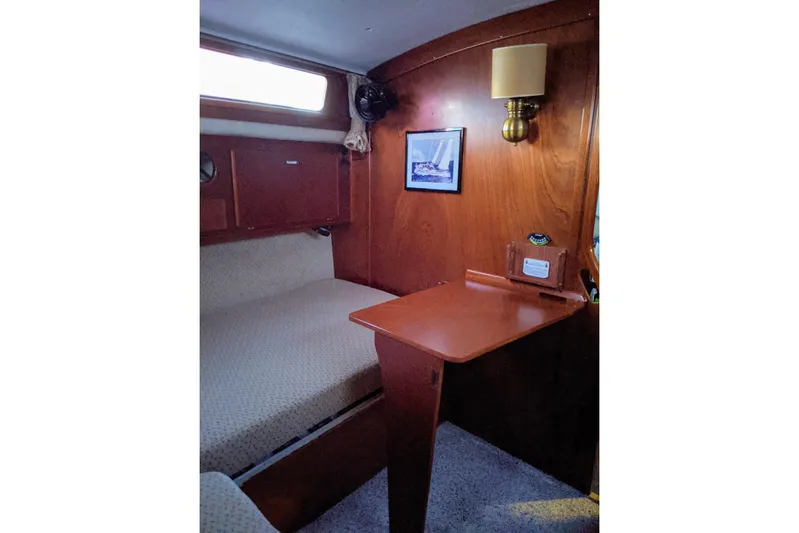 Omorfi Thea Yacht Photos Pics Cozy cabin interior of 1993 Amel Santorin sailboat with wooden desk and bed.