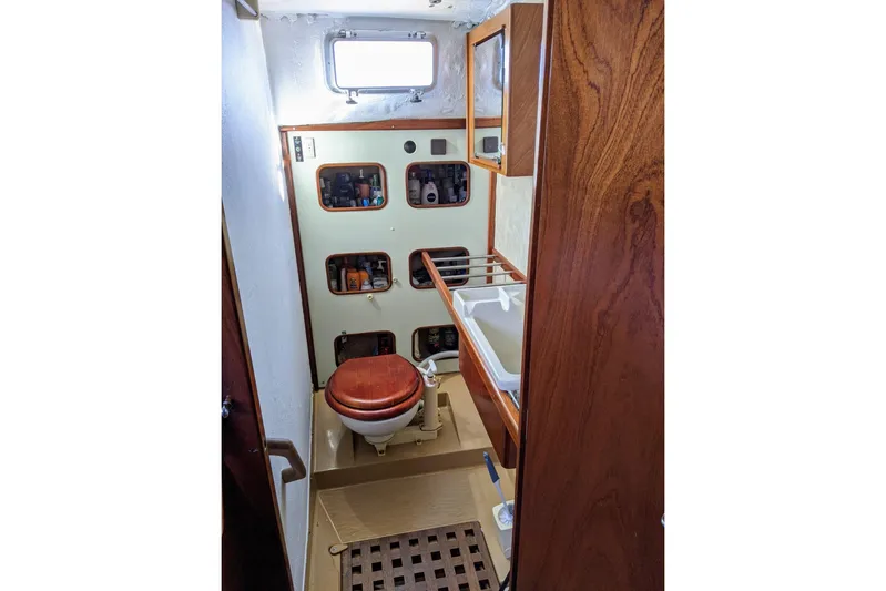 Omorfi Thea Yacht Photos Pics 1993 Amel Santorin yacht bathroom with wooden accents and storage shelves.