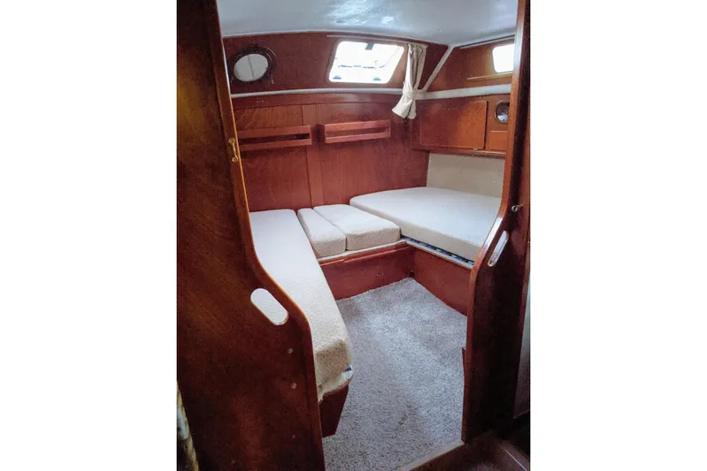 Omorfi Thea Yacht Photos Pics Cozy cabin interior of 1993 Amel Santorin sailboat with wooden finish and cushioned seating.