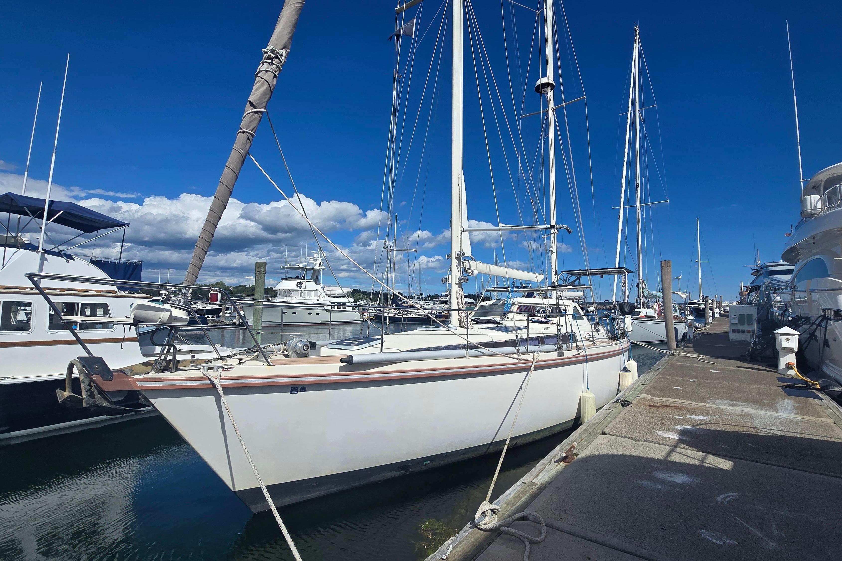 Sailboat Amel Santorin 1993 docked at marina under clear blue sky.