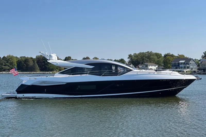  Yacht Photos Pics 2018 Sunseeker Predator 74 yacht on calm water, with houses and trees in the background.