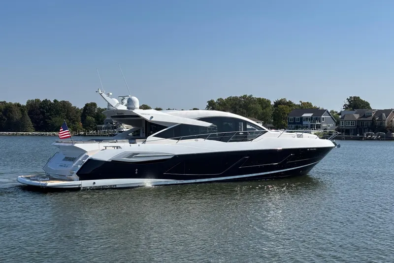  Yacht Photos Pics 2018 Sunseeker Predator 74 yacht on calm water, with American flag, near waterfront homes.