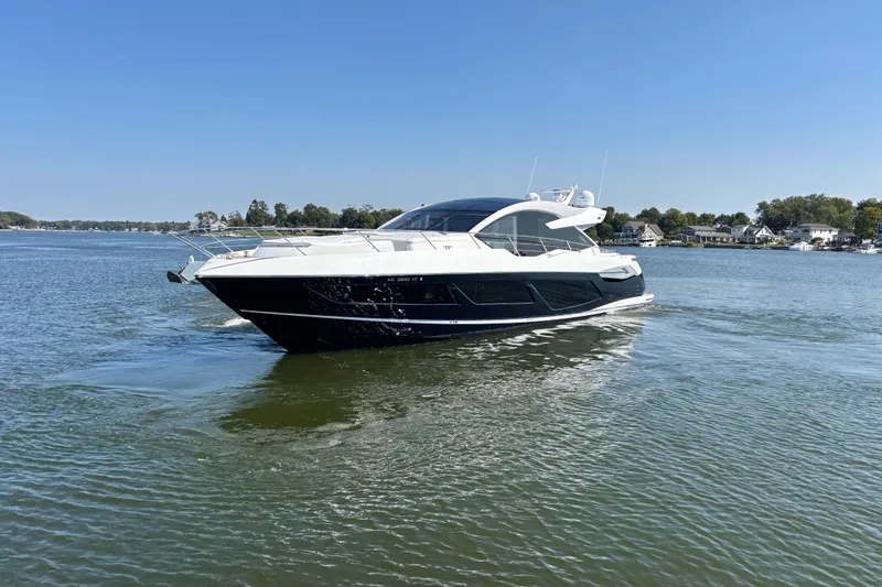  Yacht Photos Pics 2018 Sunseeker Predator 74 yacht cruising on a serene lake under a clear blue sky.