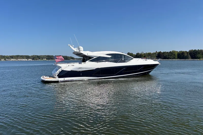  Yacht Photos Pics 2018 Sunseeker Predator 74 yacht cruising on a calm lake under clear blue skies.
