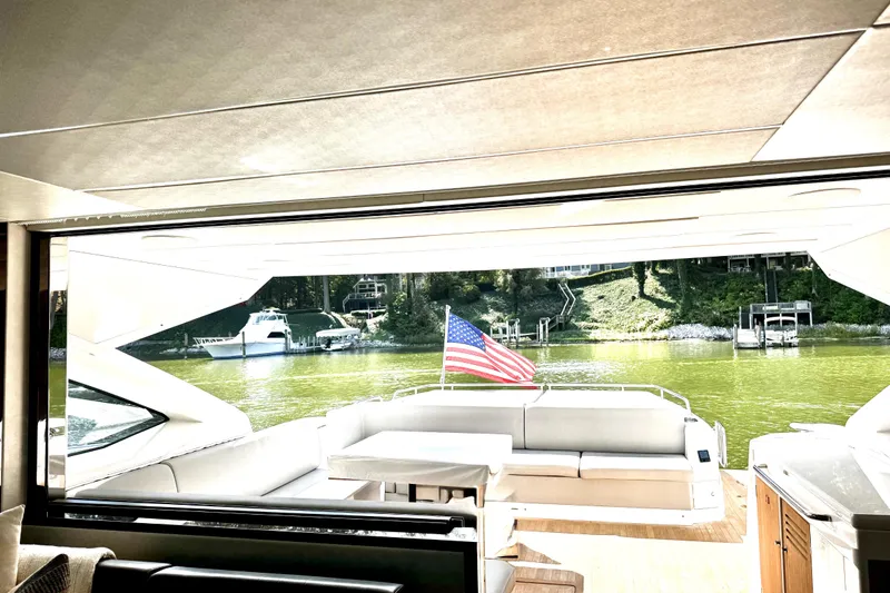  Yacht Photos Pics Interior view of 2018 Sunseeker Predator 74 yacht with American flag and scenic waterway.