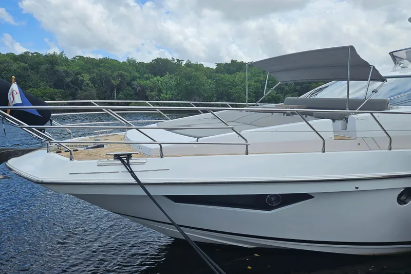  Yacht Photos Pics Azimut 66 yacht 2022 model docked by lush greenery under a cloudy sky.