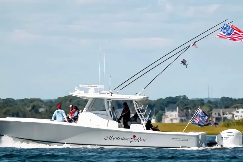  Yacht Photos Pics 2024 Regulator 37 boat cruising with flags, passengers onboard, scenic background.