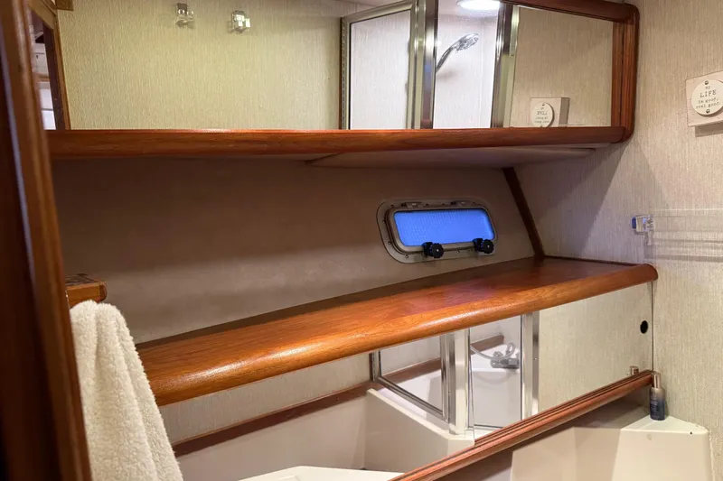 Lady Jake Yacht Photos Pics Interior of 1985 Bayliner 4550 Motoryacht bathroom with wooden shelves and porthole window.