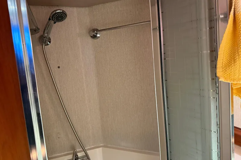 Lady Jake Yacht Photos Pics Shower area inside 1985 Bayliner 4550 Motoryacht, featuring handheld showerhead and glass door.