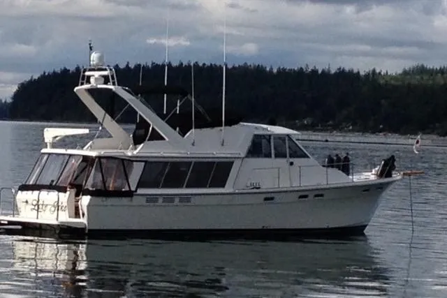Lady Jake Yacht Photos Pics 1985 Bayliner 4550 Motoryacht on calm water with forested shoreline in background.