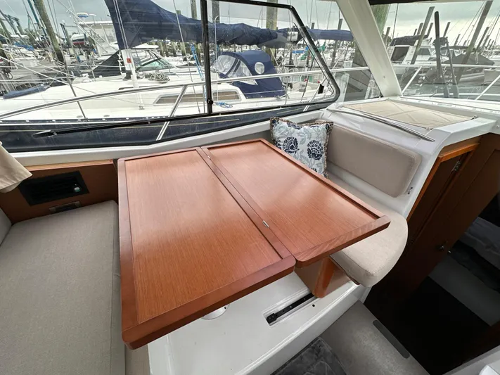 Something Special Yacht Photos Pics Interior of 2016 Jeanneau Merry Fisher 855 with wooden table and cushioned seating.