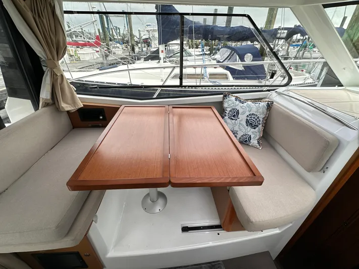 Something Special Yacht Photos Pics Interior of 2016 Jeanneau Merry Fisher 855 with wooden table and cushioned seating.
