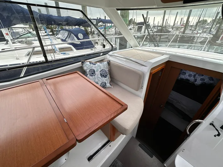 Something Special Yacht Photos Pics Interior of 2016 Jeanneau Merry Fisher 855 with wooden table and cushioned seating.