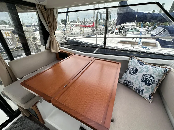 Something Special Yacht Photos Pics Interior of 2016 Jeanneau Merry Fisher 855 with wooden table and floral cushion.