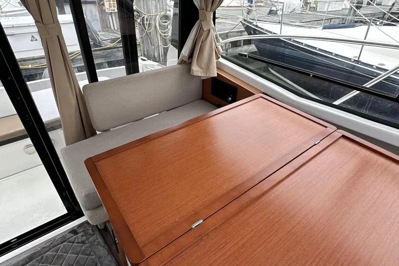 Something Special Yacht Photos Pics Interior of 2016 Jeanneau Merry Fisher 855 with wooden table and cushioned seating.