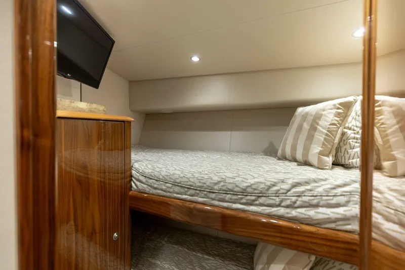 Galati Yacht Sales Trade Yacht Photos Pics 2020 Viking 62 Convertible yacht cabin with cozy bed, TV, and wooden cabinetry.