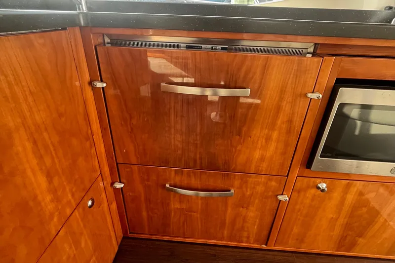  Yacht Photos Pics Wooden cabinetry in a 2015 Riviera 5000 Sport Yacht kitchen, featuring sleek metal handles.