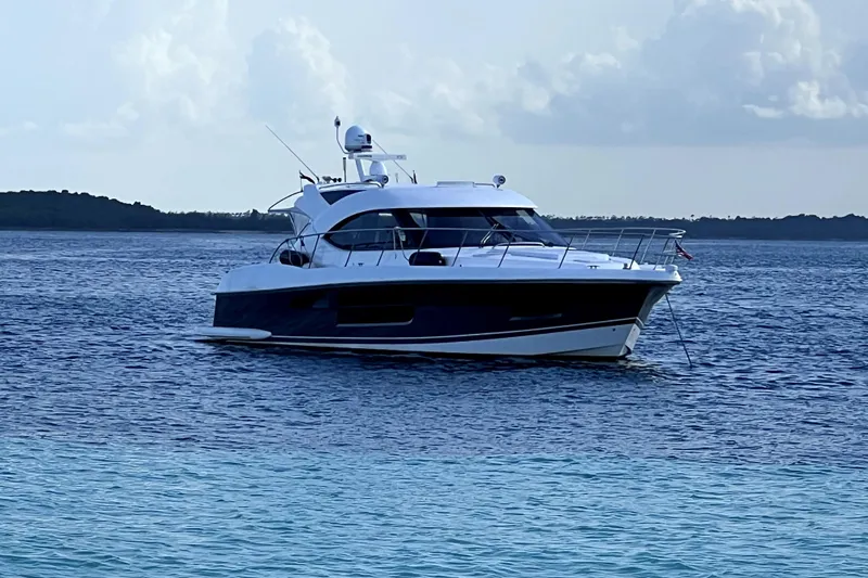  Yacht Photos Pics 2015 Riviera 5000 Sport Yacht anchored on calm blue waters under a cloudy sky.