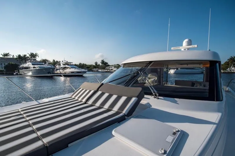  Yacht Photos Pics 2015 Riviera 5000 Sport Yacht with sunbed, docked in a serene marina setting.