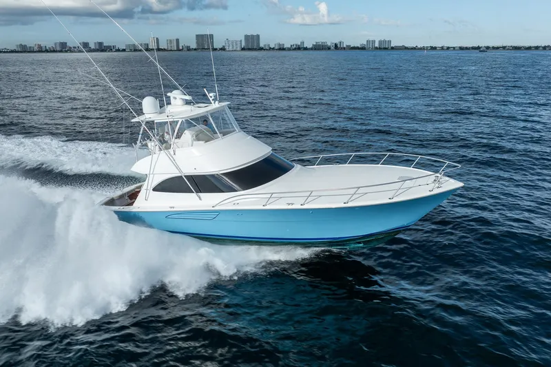 Lori A Yacht Photos Pics 2021 Viking 54 Convertible yacht cruising on open water, city skyline in background.