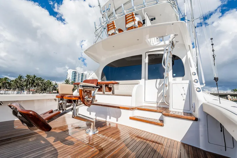 Lori A Yacht Photos Pics 2021 Viking 54 Convertible yacht with teak deck and fishing chair, under a partly cloudy sky.